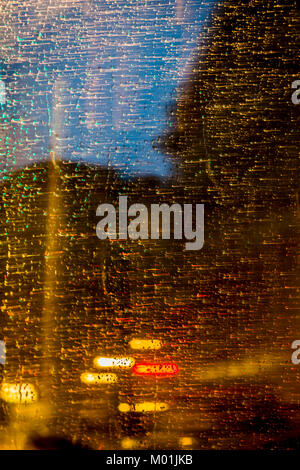Gouttes de pluie sur la fenêtre du train. Les gouttes de pluie couler le long de la fenêtre du train, le soir les lumières de la ville, à l'extérieur. Banque D'Images