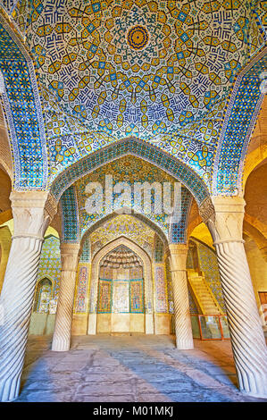 SHIRAZ, IRAN - 12 octobre 2017 : l'shabestan (salle de prière) de la mosquée Vakil avec vue sur mihrab et dômes, richement décorée avec un sol carrelé patt islamique Banque D'Images