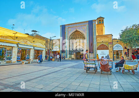 SHIRAZ, IRAN - 12 octobre 2017 : Les portiers se détendre, assis sur leurs charrettes vides, à l'entrée principale de la mosquée Vakil Bazar Vakil et - le principal tou Banque D'Images