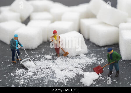 Les gens miniature balayer le sucre. Soins de santé et la neige concept. L'alimentation, la graisse et le diabète. Concept de soins de santé. Banque D'Images