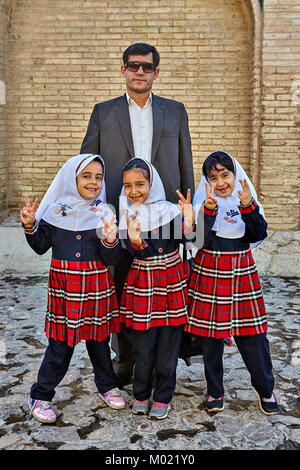 Isfahan, Iran - le 24 avril 2017 : trois jeunes filles iraniennes smiling inconnue d'âge primaire sont photographiés avec un homme mûr, père, ou de l'enseignant. Banque D'Images