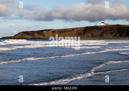 Vue d'une maison blanche sur les falaises de la plage de sable fin de Porth, Tywyn Mawr, Llanfwrog, Anglesey, à travers l'arrivée d'eau Banque D'Images