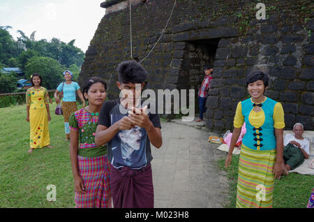 Mrauk-U, l'État de Rakhine/ Myanmar - 18 octobre 2016 : traditionnellement habillé des adolescents et un jeune homme avec un téléphone mobile contrairement à un vieux mendiant Banque D'Images