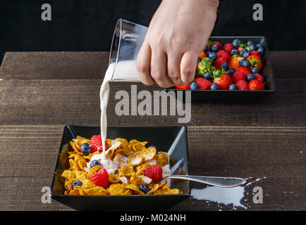 Les céréales et fruits rouges dans un bol carré noir petit-déjeuner le matin avec du lait Banque D'Images