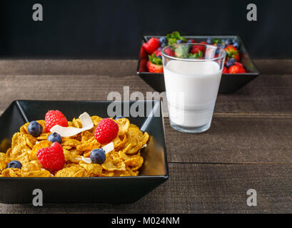 Les céréales et fruits rouges dans un bol carré noir petit-déjeuner le matin avec du lait Banque D'Images