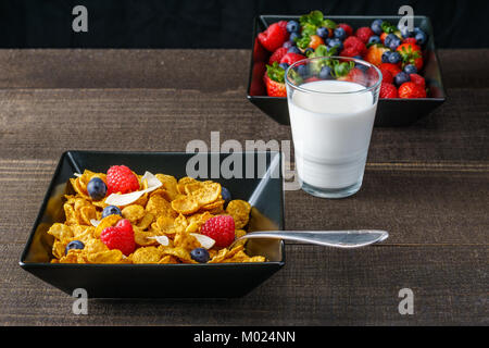 Les céréales et fruits rouges dans un bol carré noir petit-déjeuner le matin avec du lait Banque D'Images