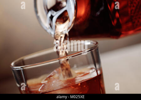 Whiskey est versé d'une carafe en verre avec de la glace. Banque D'Images