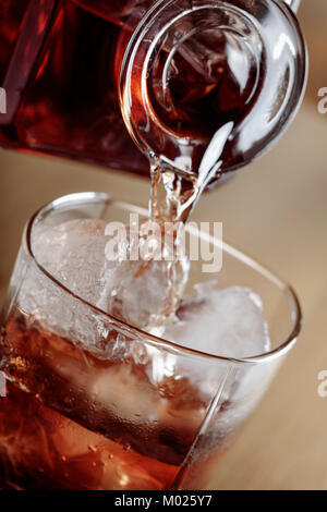 Whiskey est versé d'une carafe en verre avec de la glace. Banque D'Images