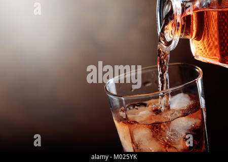 Whiskey est versé d'une carafe en verre avec de la glace.Copier l'espace. Banque D'Images