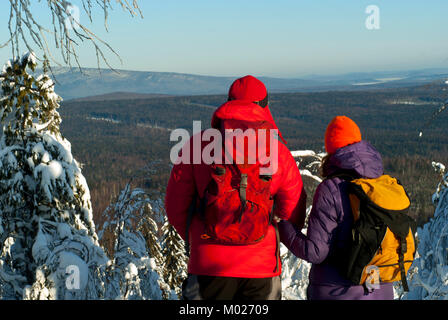 L'homme et la femme les randonneurs se tenir avec le dos de l'observateur au sommet de la montagne en hiver et de se pencher sur la distance Banque D'Images