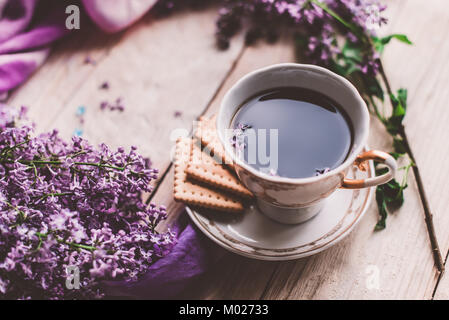 Tasse de thé, biscuits, et lilas fleur sur table en bois à partir de ci-dessus. Beau petit-déjeuner. Mise à plat style avec copie espace Banque D'Images