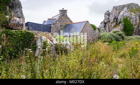 Voyage en France - maison en pierre typiquement breton et rochers à Plougrescant ville des Côtes-d'Armor en Bretagne au jour d'été pluvieux Banque D'Images