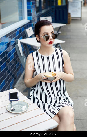 Femme au bar d'un café extérieur minidress looking away Banque D'Images