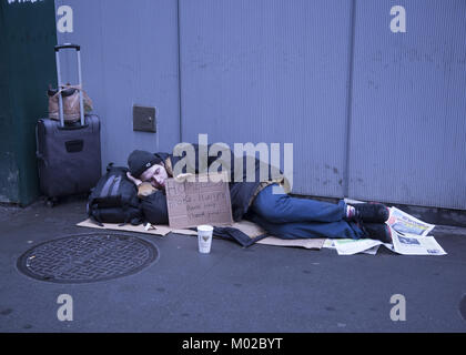 Les jeunes sans-abri dort le long de Broadway avec un signe de demander de l'aide dans le quartier financier de Manhattan. NYC. Banque D'Images