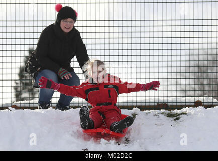 Cinq ans Dani Paterson avec mère Sally la luge dans la neige à Selkirk as police exhortent les automobilistes de conduire avec "une extrême prudence" au milieu des conditions hivernales en Ecosse. Banque D'Images