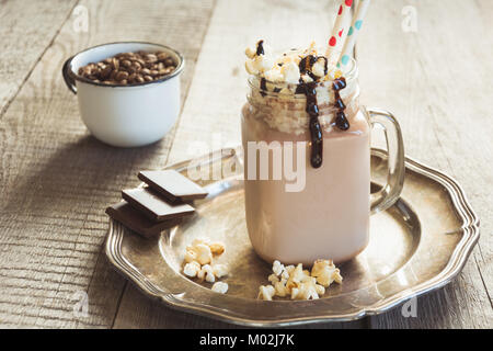 Café au Chocolat milkshake avec crème fouettée servi en pot Mason en verre gris sur fond de bois. Boisson sucrée. Banque D'Images