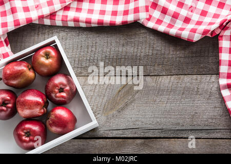 Pommes rouges bien mûrs en bouleau-box sur planche de bois avec une serviette autour de rouge à carreaux et copier l'espace. Banque D'Images