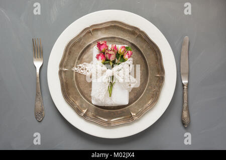 Réglage de la table de fête, avec des fleurs, cadeaux femme vintage vaisselle, l'argenterie et des décorations sur le gris. Vue d'en haut. Concept. Banque D'Images