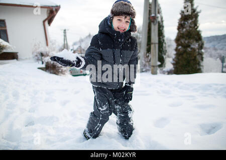 Rire dans l'enfant des vêtements chauds s'amusant pendant une bataille de boules de neige. Garçon dans la neige. Banque D'Images
