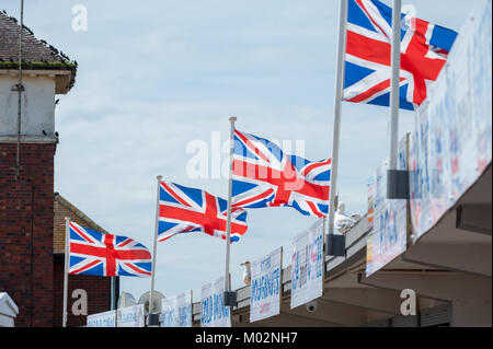 Union Jack drapeaux flottants sur fast food signes et contre un ciel bleu sur une journée d'été sur le front de mer de Littlehampton, West Sussex. Banque D'Images