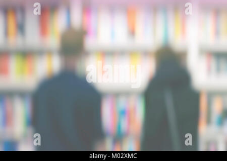 Silhouettes de deux jeunes gens qui étudient avec intérêt des étagères de livres sur des étagères dans la bibliothèque ou dans une librairie, un fond flou, le style de vie, la lecture, l'éducation Banque D'Images
