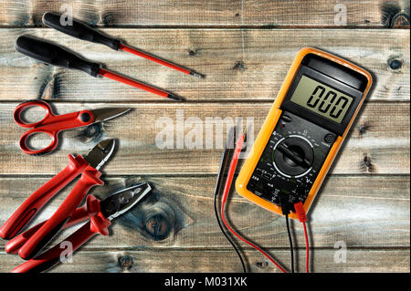 Multimètre, pince, ciseaux, coupe-câbles et de tournevis pour travailler sur un système électrique résidentielle photographié sur un ancien bureau en bois. Banque D'Images