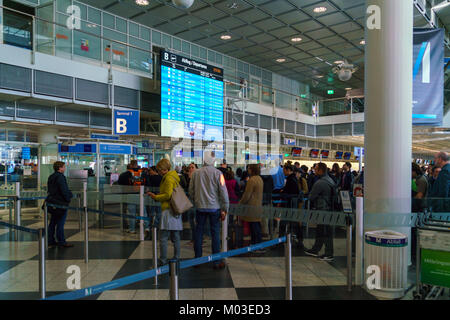 Munich, Allemagne - 14 octobre 2017 : Les passagers se tenir en face de l'horaire de départ sur une carte électronique à l'aéroport. Banque D'Images