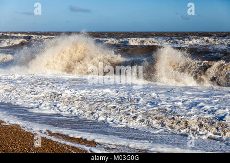 Vagues se brisant sur le rivage d'une plage de galets avec mousse à l'avant-plan contre un horizon horizontal avec ciel bleu Banque D'Images