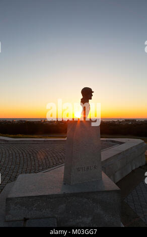 NC01338-00...CAROLINE DU NORD - Lever du soleil sur l'Océan Atlantique derrière le buste de Wilbur Wright à la base du monument à l'Wright Brothers Nati Banque D'Images