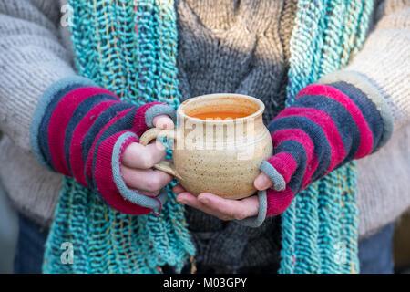 Femme portant des gants de laine colorés tenant une tasse de soupe de tomate en hiver. UK Banque D'Images