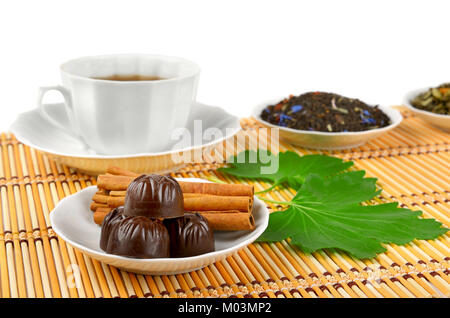 Tasse de thé, chocolat et cannelle sur le tapis de bambou sur fond blanc Banque D'Images