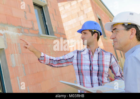 Foreman pointing at maison inachevée Banque D'Images