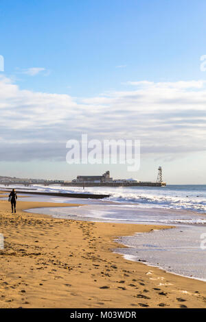 Bournemouth, Dorset, UK. 18 janvier, 2018. Météo France : après une nuit très ventée une belle journée ensoleillée à la plage de Bournemouth. Femme marche le long de la plage passé les grandes vagues et mer agitée. Credit : Carolyn Jenkins/Alamy Live News Banque D'Images