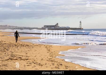 Bournemouth, Dorset, UK. 18 janvier, 2018. Météo France : après une nuit très ventée une belle journée ensoleillée à la plage de Bournemouth. Femme marche le long de la plage passé les grandes vagues et mer agitée. Credit : Carolyn Jenkins/Alamy Live News Banque D'Images