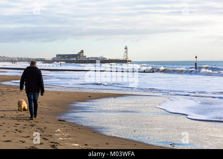 Bournemouth, Dorset, UK. 18 janvier, 2018. Météo France : après une nuit très ventée une belle journée ensoleillée à la plage de Bournemouth. L'homme chien promenades le long du littoral depuis les grandes vagues et mer agitée. Credit : Carolyn Jenkins/Alamy Live News Banque D'Images