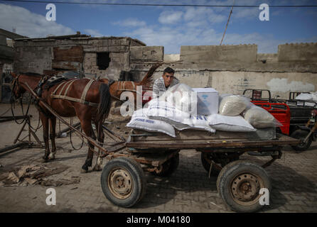 Un Palestinien de l'aide des charges fournis par l'organisation des secours et de travaux des Nations Unies pour les réfugiés de Palestine dans le Proche-Orient (UNRWA) sur un cheval panier à un centre de distribution alimentaire dans l'al-camp de réfugiés de Shati à Gaza, Gaza, 18 janvier 2018. L'UNRWA, l'agence des Nations Unies responsable de Palestiniens, lancera une campagne mondiale de collecte de fonds pour compenser pour des dizaines de millions de dollars retenus par le président américain Donald Trump. L'Office prend en charge quelque 5 million de palestiniens en Jordanie, en Syrie, au Liban et dans les territoires palestiniens. Photo : Wissam Nassar/dpa Banque D'Images