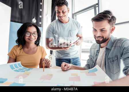 Smiling young people de coopérer sur le projet de bureau en étain Banque D'Images