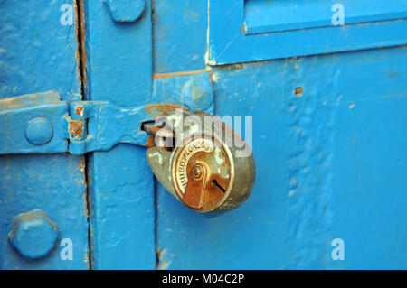 Un vieux cadenas rouillé sur une porte peinte en bleu et en fer ou acier et sauterelle ou mécanisme de fermeture condamnation. ancien écaillage et d'exfoliation peinte en bleu. Banque D'Images