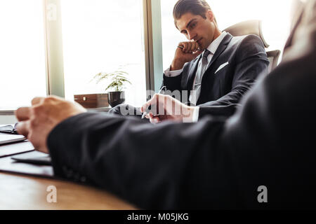 Thoughtful businessman assis à son bureau et à son partenaire à prendre des notes. Les gens d'affaires de l'entreprise travaillent ensemble dans le bureau. Banque D'Images