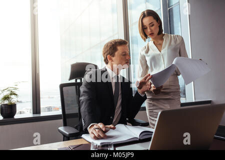 Deux jeunes gens d'affaires d'analyser les résultats et en discuter. Businessman with female colleague lecture des documents au bureau. Banque D'Images