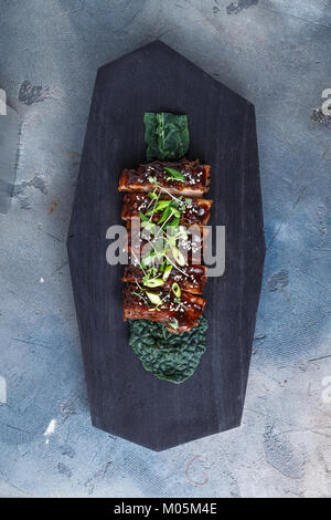 Bbq ribs glacées au miel sur tableau noir, vue du dessus de l'espace de copie. Banque D'Images