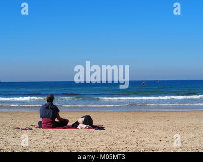 Les loisirs en vacances - couple est allongé et assis ensemble au soleil sur une plage de sable Banque D'Images