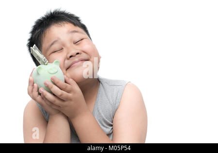 Happy fat boy sourire avec de l'argent et tirelire isolé sur fond blanc, l'épargne et concept riche Banque D'Images