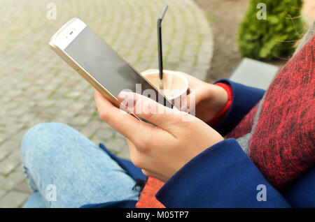 D'un téléphone et d'une tasse de café dans les mains des femmes. Sur les ongles est un beau vernis beige, une belle manucure. Photo horizontale Banque D'Images