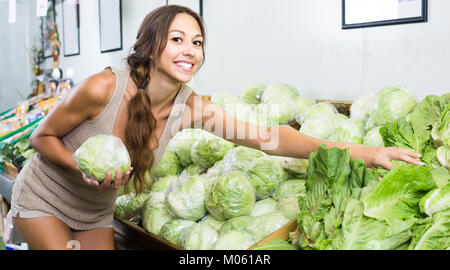 Souriante jeune femme joyeuse vert frais d'achat des clients en magasin salade iceberg Banque D'Images