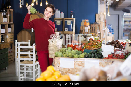 Jeune femme espagnole choisissant les artichauts dans un magasin d'alimentation à la ferme Banque D'Images