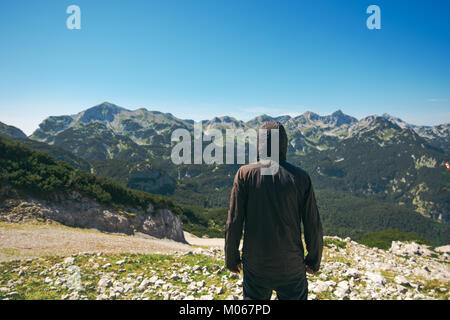 Le randonneur à vue à haute de la vallée. L'homme personne en veste en haut de la montagne à profiter de la vue. Banque D'Images