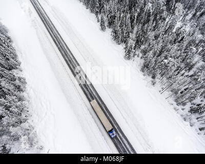 De vitesse semi-remorque camion est sur un terrain glissant, l'autoroute de l'asphalte en hiver Vue de dessus de drone Banque D'Images