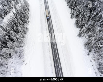 Camion semi-remorque blanc en route vers rapide sur une route asphaltée d'hiver glissante, vue aérienne de drone Banque D'Images