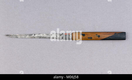 Un kozuka est un manche décoratif pour un petit couteau utilitaire (kogatana), souvent inséré dans une fente au dos d'un fourreau katana. Fabriqué à partir de matériaux comme le cuivre, l'alliage cuivre-or (shakudō), l'or et l'acier, il met en valeur l'artisanat traditionnel et l'utilisation de matériaux dans les armes et les objets personnels à son époque. Banque D'Images